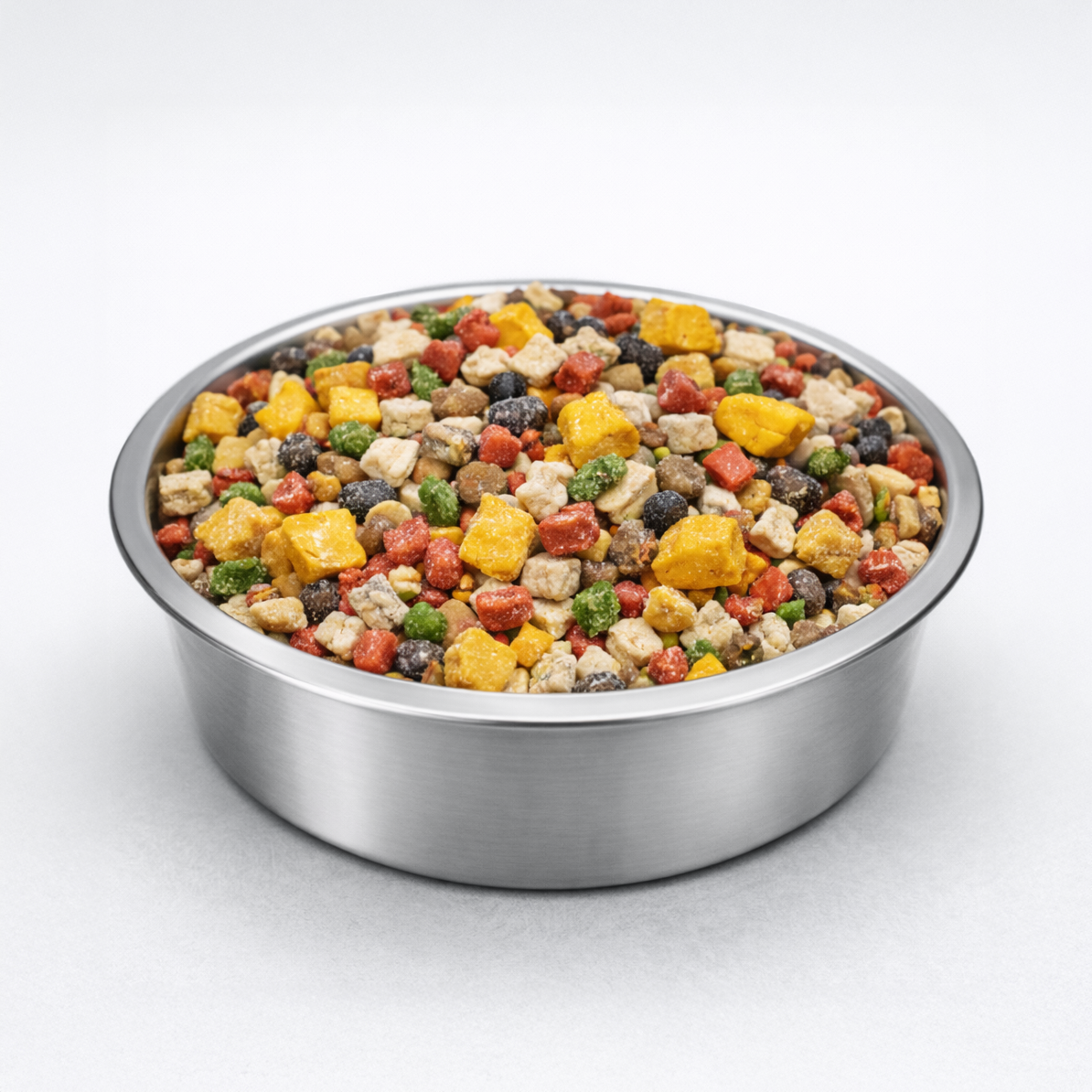 Stainless steel bowl filled with freeze-dried dog meal mixer, showing colorful raw ingredients and kibble pieces on a clean, neutral background