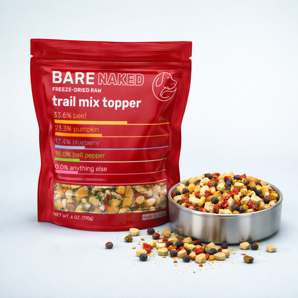 Freeze-dried dog trail mix topper shown with red resealable pouch and stainless steel bowl filled with mixed raw ingredients on a clean, neutral background
